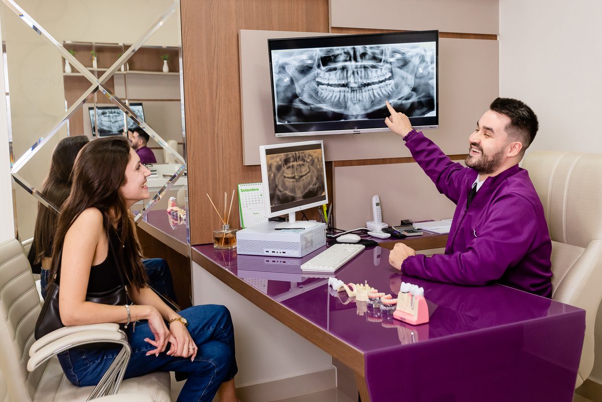 Dentista da Oral Unic Encantado explicando o plano de tratamento de implante ao paciente