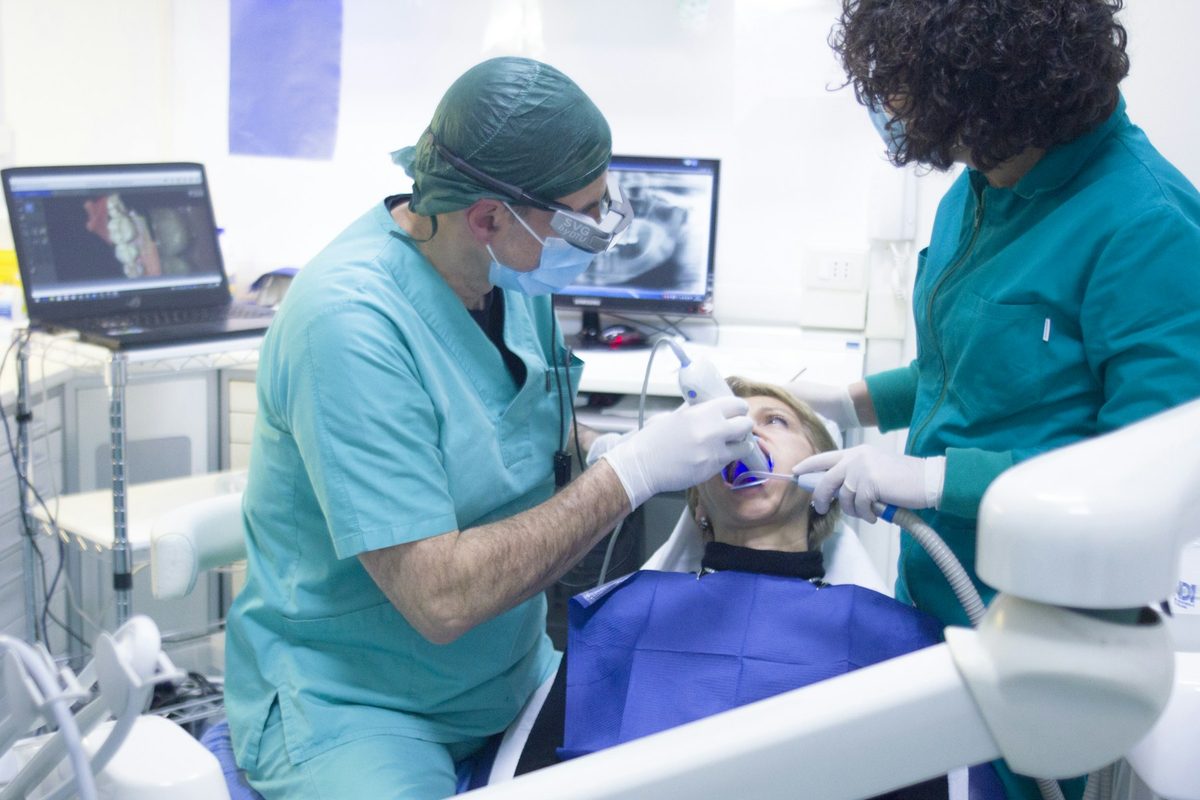 Equipe odontológica em procedimento cirúrgico com planejamento por imagem na tela